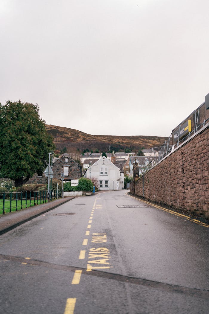 A peaceful, empty street in Fort William, Scotland under a cloudy sky showcasing natural beauty.
